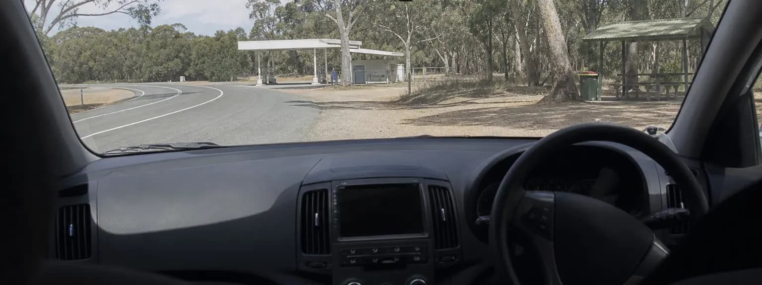 Fuel stop planning inside a parked right-hand-drive vehicle at an Australian highway rest area